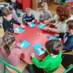 Dzieci przy stoliku wykonują pracę plastyczną
