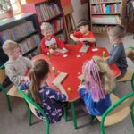 Dzieci przy stoliku wykonują pracę plastyczną