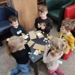 Dzieci przy stoliku wykonują pracę plastyczną