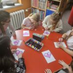 Dzieci przy stoliku wykonują pracę plastyczną