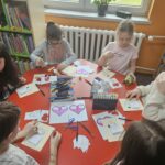 Dzieci przy stoliku wykonują pracę plastyczną