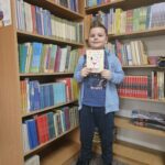 Chłopak, uczestnik spotkania, prezentujący wykonaną przez siebie pracę plastyczną