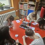 Dzieci przy stoliku wykonują pracę plastyczną