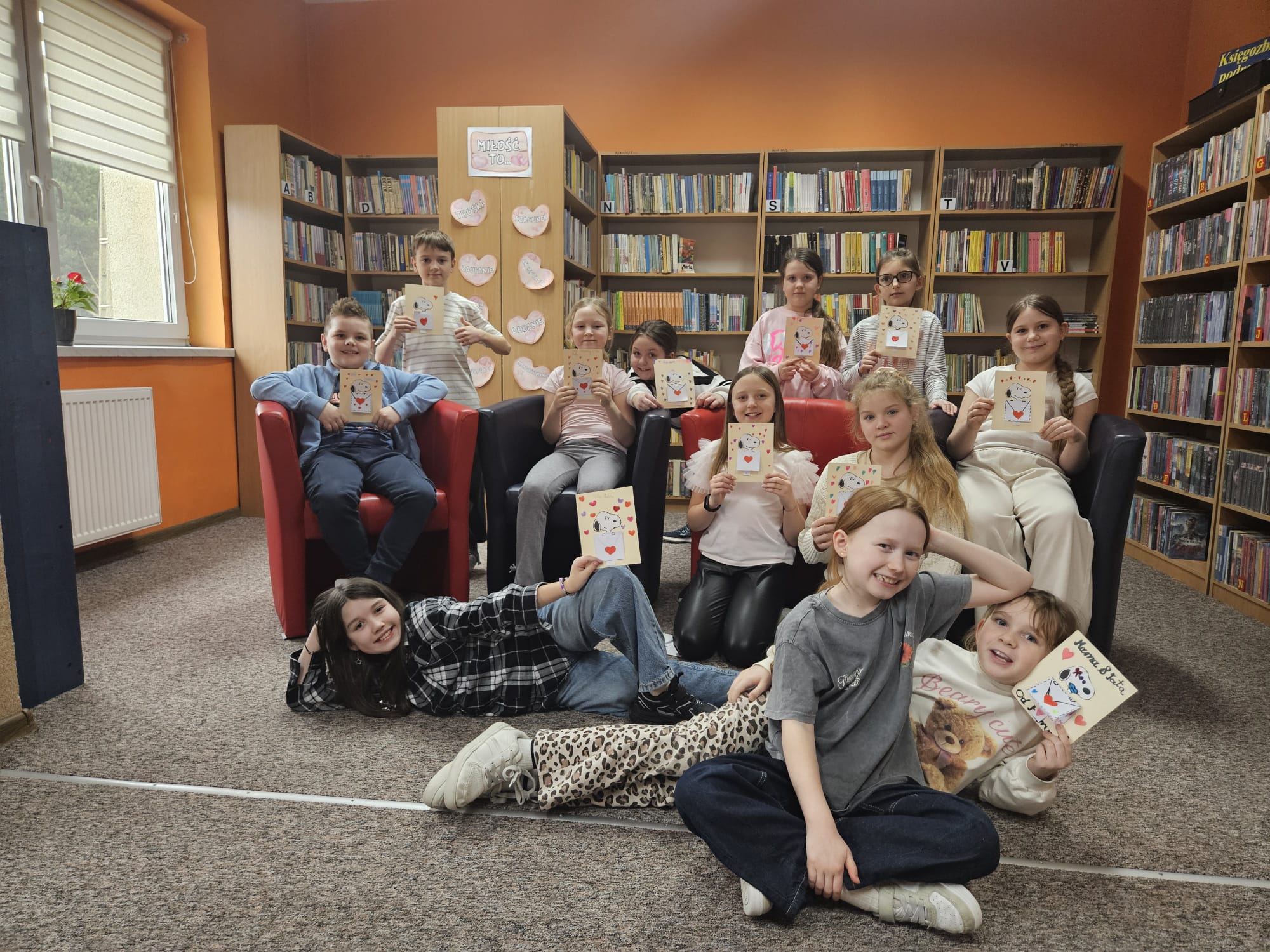 Zdjęcie grupowe uczestników spotkania prezentujących wykonane przez siebie prace plastyczne