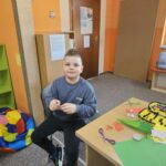 Chopak przy stoliku wykonuje pracę plastyczną