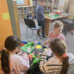 Dzieci przy stoliku wykonują pracę plastyczną