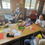 Dzieci przy stoliku wykonują pracę plastyczną