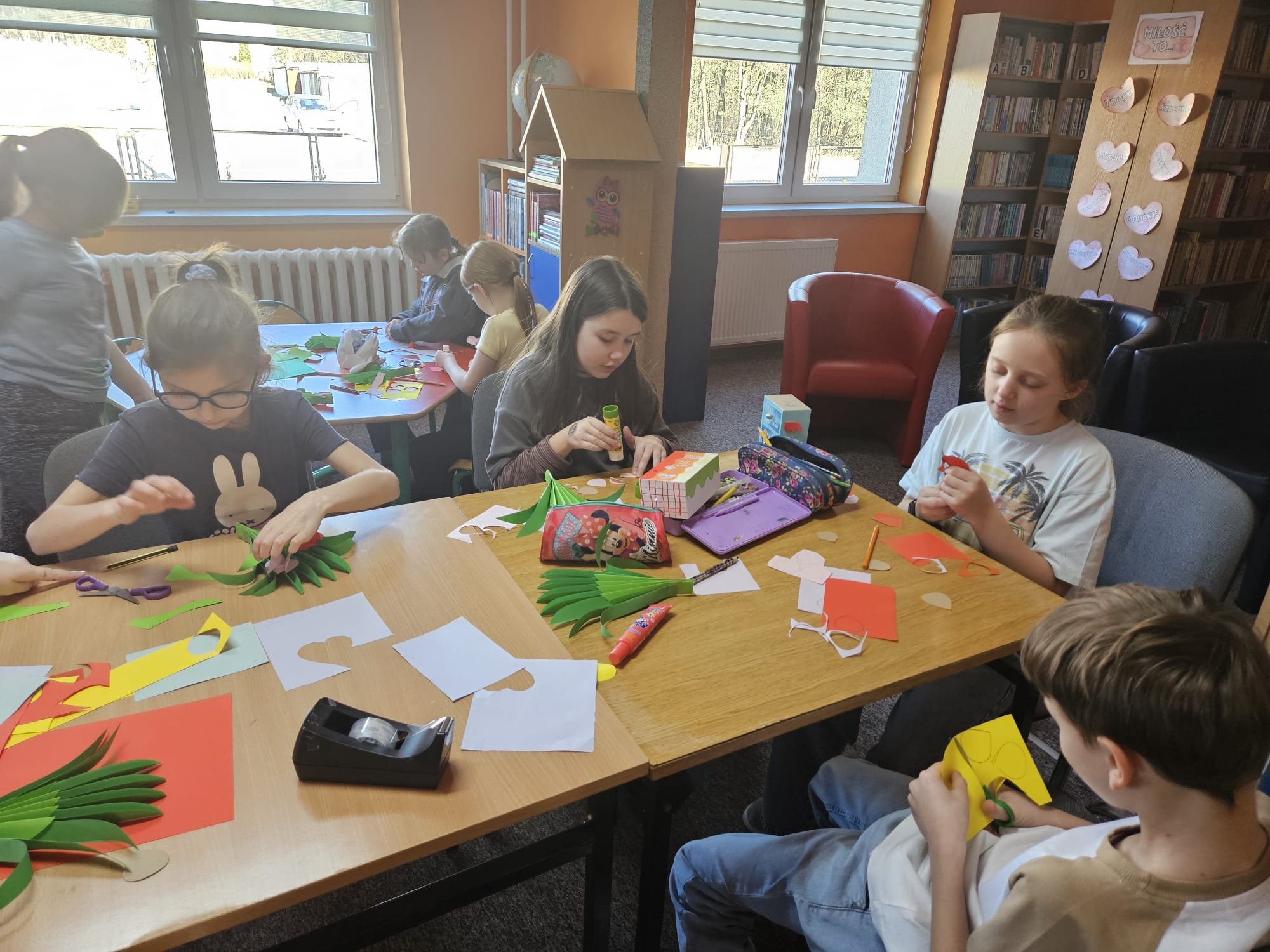 Dzieci przy stoliku wykonują pracę plastyczną