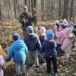 Grupa dzieci na wycieczce do lasu podczas spotkania z Panem Czesławem Tyrolem