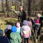 Grupa dzieci na wycieczce do lasu podczas spotkania z Panem Czesławem Tyrolem