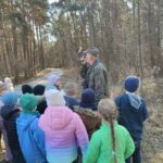 Grupa dzieci na wycieczce do lasu podczas spotkania z Panem Czesławem Tyrolem