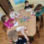 Dzieci przy stoliku wykonują pracę plastyczną