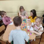 Dzieci przy stoliku wykonują pracę plastyczną