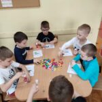 Dzieci przy stoliku wykonują pracę plastyczną