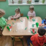 Dzieci przy stoliku wykonują pracę plastyczną