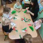 Dzieci przy stoliku wykonują pracę plastyczną