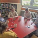 Dzieci przy stoliku wykonują pracę plastyczną