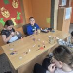 Dzieci przy stoliku wykonują pracę plastyczną