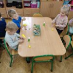 Dzieci przy stoliku wykonują pracę plastyczną