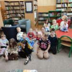 Dzieci siedzą na ziemi i z uwagą słuchają opowiadania