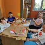 Dzieci przy stoliku wykonują pracę plastyczną