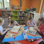 Dzieci przy stoliku wykonują pracę plastyczną