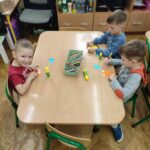 Dzieci przy stoliku w bibliotece wykonują pracę plastyczną