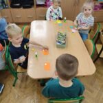 Dzieci przy stoliku w bibliotece wykonują pracę plastyczną