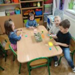 Dzieci przy stoliku w bibliotece wykonują pracę plastyczną