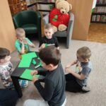 Dzieci przy stoliku wykonują pracę plastyczną