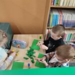 Dzieci przy stoliku wykonują pracę plastyczną
