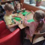 Dzieci przy stoliku wykonują pracę plastyczną
