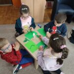 Dzieci przy stoliku wykonują pracę plastyczną