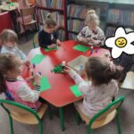 Dzieci przy stoliku wykonują pracę plastyczną