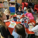 Dzieci przy stoliku wykonują pracę plastyczną