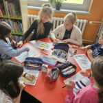 Dzieci przy stoliku wykonują pracę plastyczną
