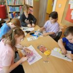 Dzieci przy stoliku wykonują pracę plastyczną
