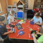 Dzieci przy stoliku wykonują pracę plastyczną