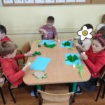 Dzieci siedzą przy stole i wykonują pracę plastyczną