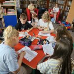 Dzieci przy stoliku wykonują pracę plastyczną