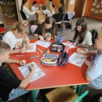 Dzieci przy stoliku wykonują pracę plastyczną