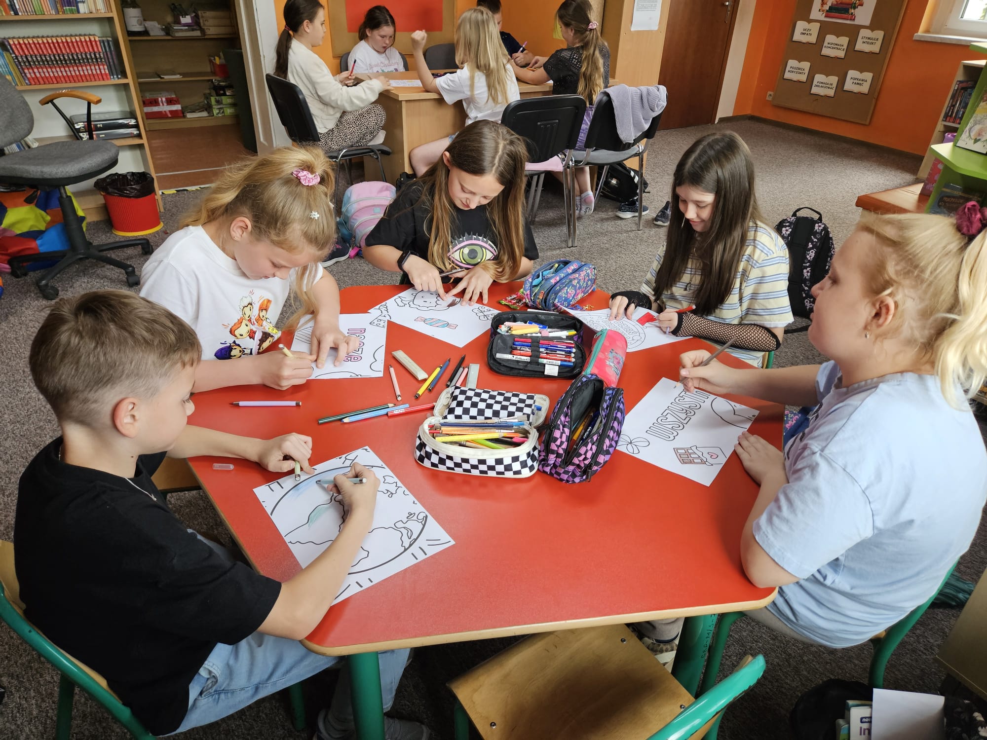 Dzieci przy stoliku wykonują pracę plastyczną