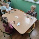 Dzieci przy stoliku wykonują pracę plastyczną