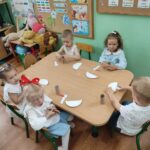 Dzieci przy stoliku wykonują pracę plastyczną