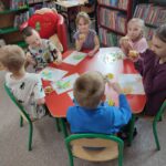 Dzieci przy stoliku z pamiątkowymi dyplomami i delektują się przygotowanymi specjalnie dla nich babeczkami.