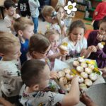 Dzieci przy stoliku z pamiątkowymi dyplomami i delektują się przygotowanymi specjalnie dla nich babeczkami.