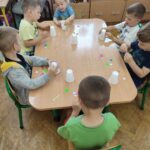 Dzieci przy stoliku wykonują pracę plastyczną