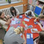 Dzieci przy stoliku wykonują pracę plastyczną