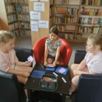 Dzieci przy stoliku wykonują pracę plastyczną