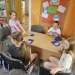 Dzieci przy stoliku wykonują pracę plastyczną